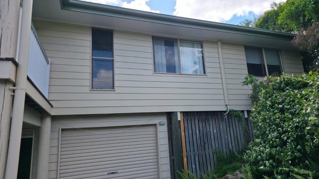 Freshly painted cream weatherboard home with garage and landscaped front garden