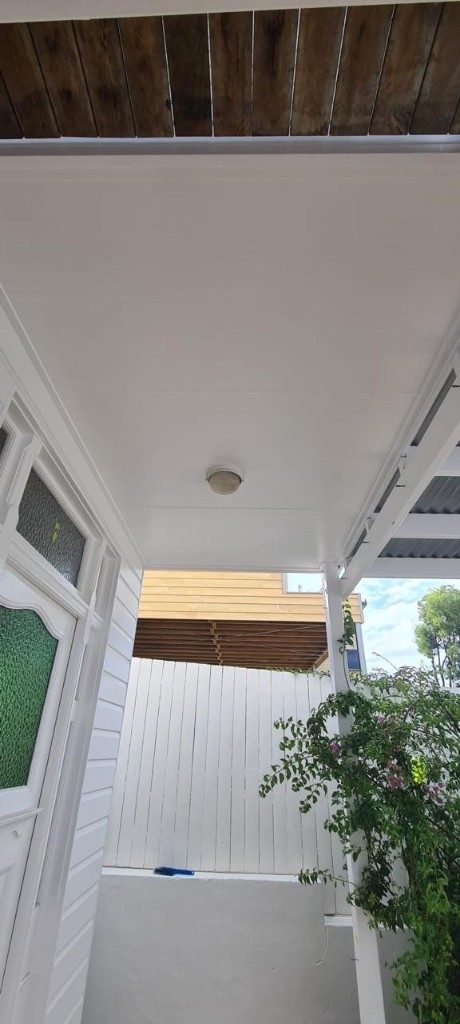 White painted porch awnings and weatherboard with charcoal window frames